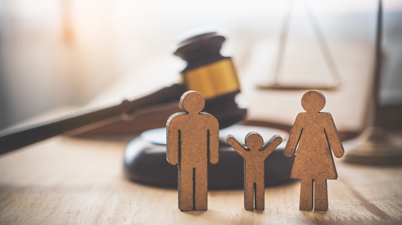 a group of wooden figures of a family in lawyer scales background