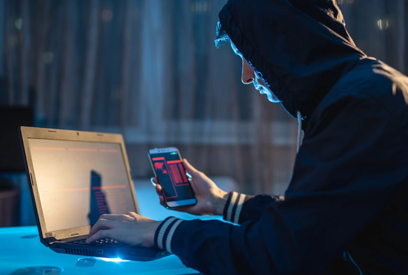 A person wearing a hoodie is busy working on a laptop computer. Cybersecurity practices for attorney.