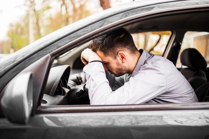 At-fault driver has no insurance rests his head on the steering whee